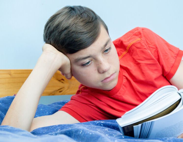 boy on bed in red shirt reading